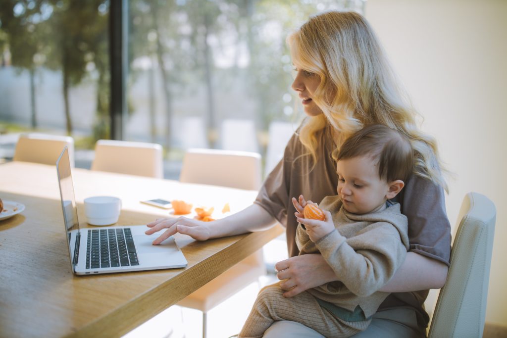 Starting over context, woman working on laptop with toddler sitting on her lap