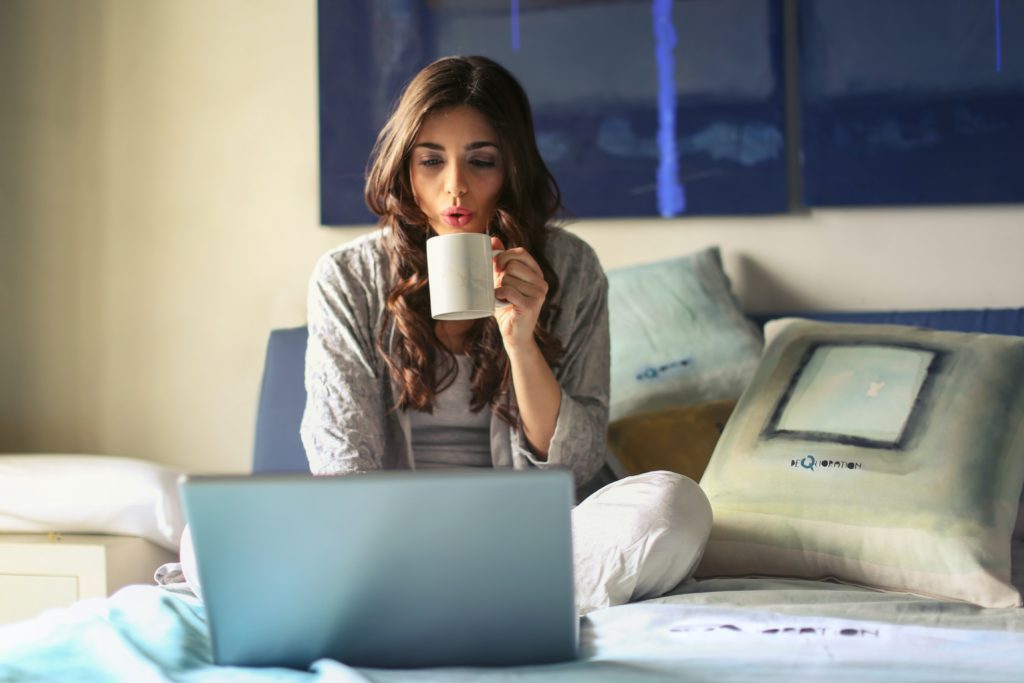 Pinterest context, woman sitting on bed with coffee and laptop